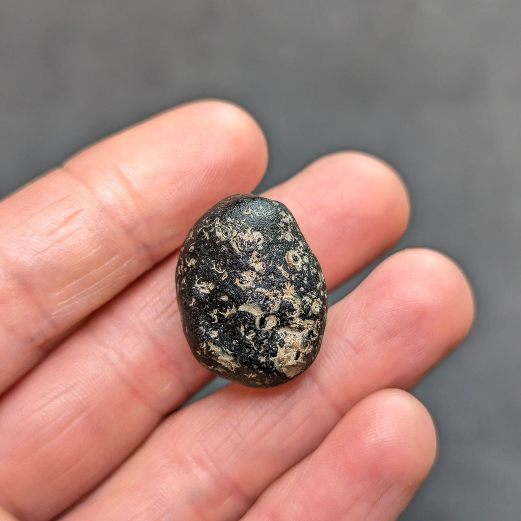 Natural Moldavite from the Zliv locality weighing 7.12 g with rounded oval pebble-like form, naturally worn surface, subtle remaining pits and preserved solid core characteristic of field-found specimens - back view.
