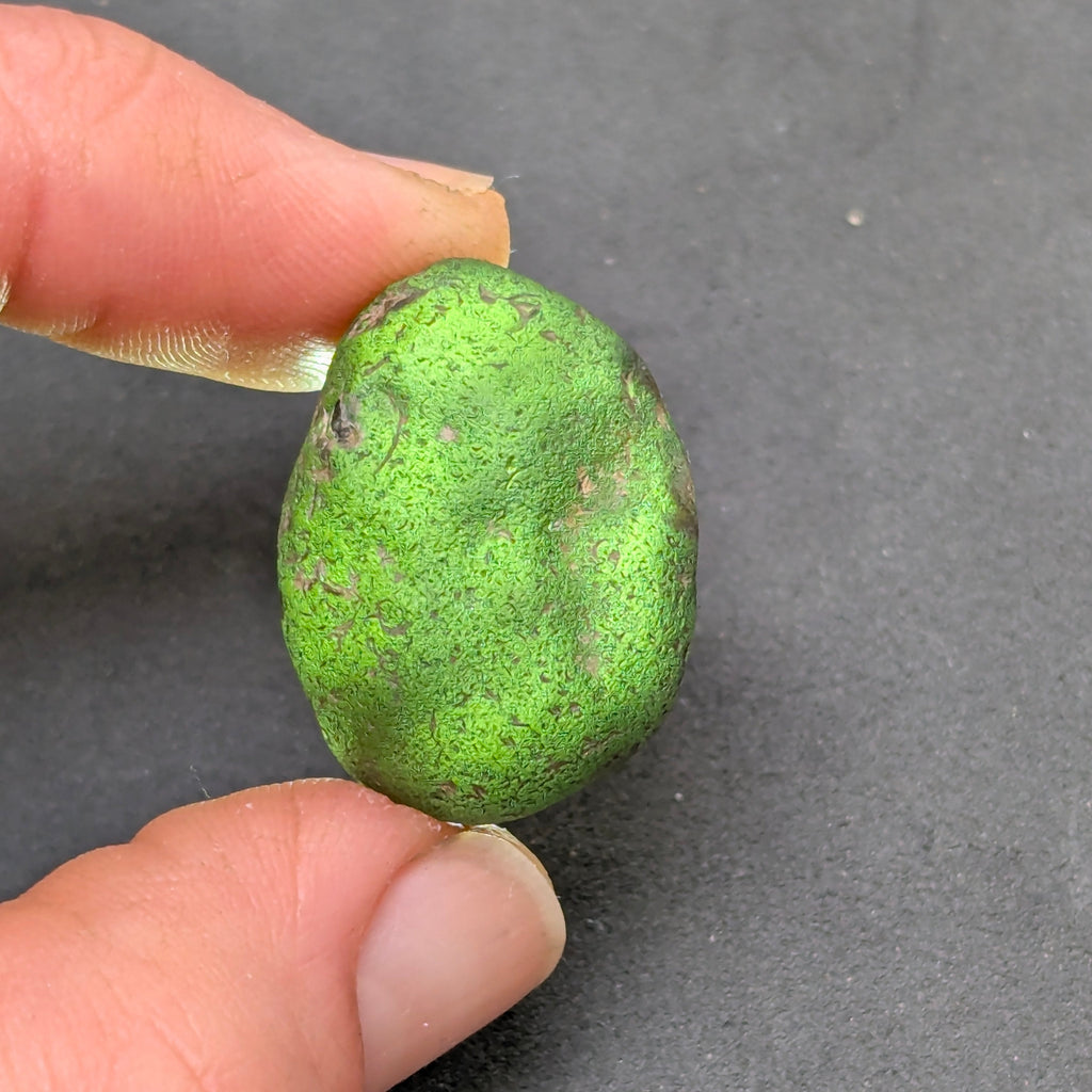 Natural Moldavite from the Zliv locality weighing 7.12 g with rounded oval pebble-like form, naturally worn surface, subtle remaining pits and preserved solid core characteristic of field-found specimens - front view, backlight.