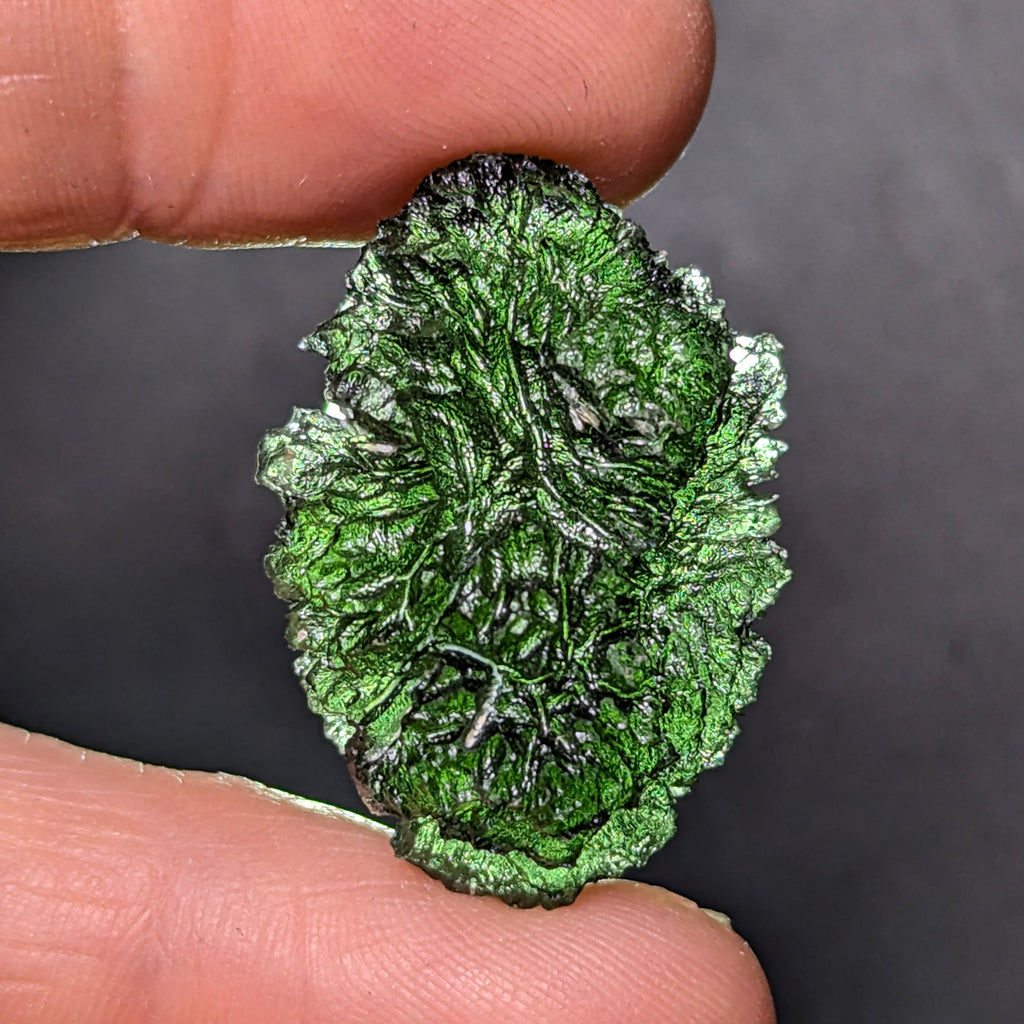 Natural Moldavite from the Olešnice locality weighing 5.67 g with egg-shaped form, deep sharply textured sculpture, rich green translucency and preserved natural surface - front view, backlight.