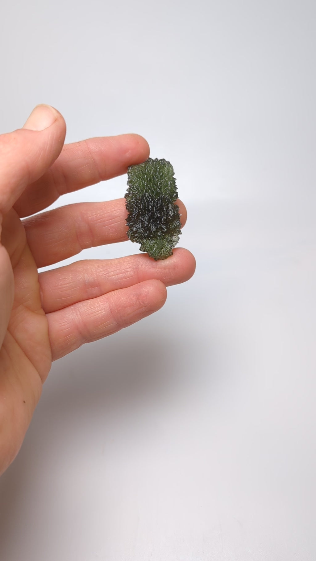 Natural Moldavite from the Dobrovská Lhotka – Bažina locality with rich sculpture, serrated edges, saturated olive green color and pronounced surface texture in hand - video.