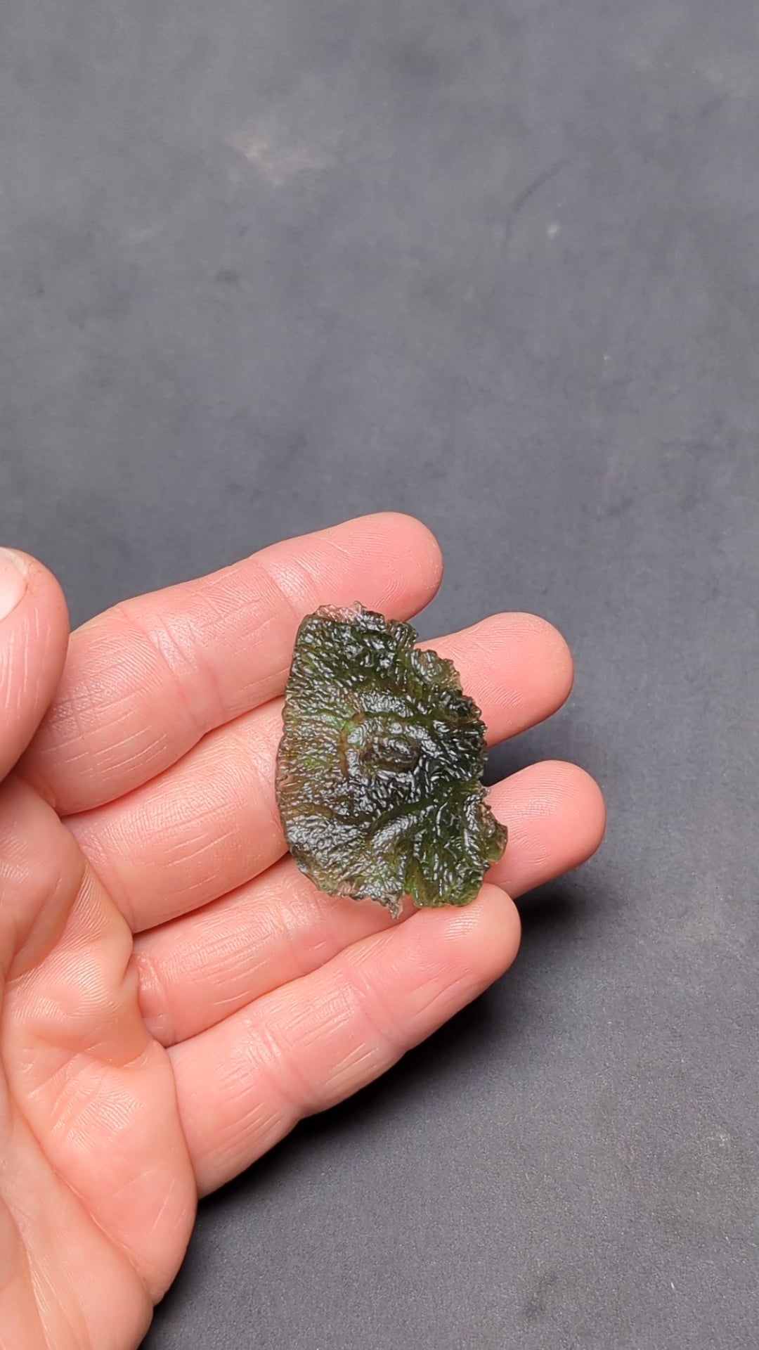 Natural Moldavite from the Olešnice locality with electrifying neon green color, glossy luster, deep grooves and vivid green translucency under illumination in hand – video.