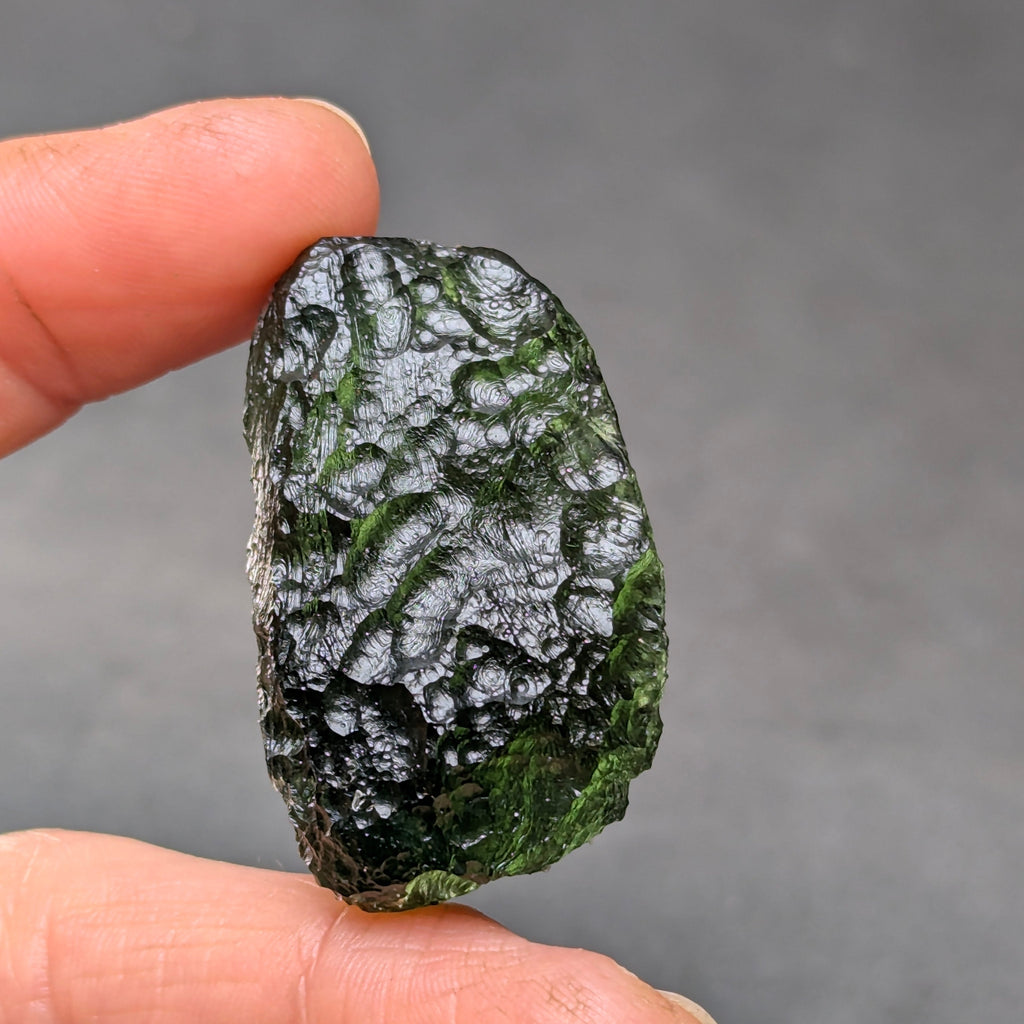 Natural Moldavite from the Krasejovka locality on white background with glossy lacquer-like surface, deep sculpture, pronounced grooves, vivid green translucency and authentic natural relief. Weight 14 g - back side.