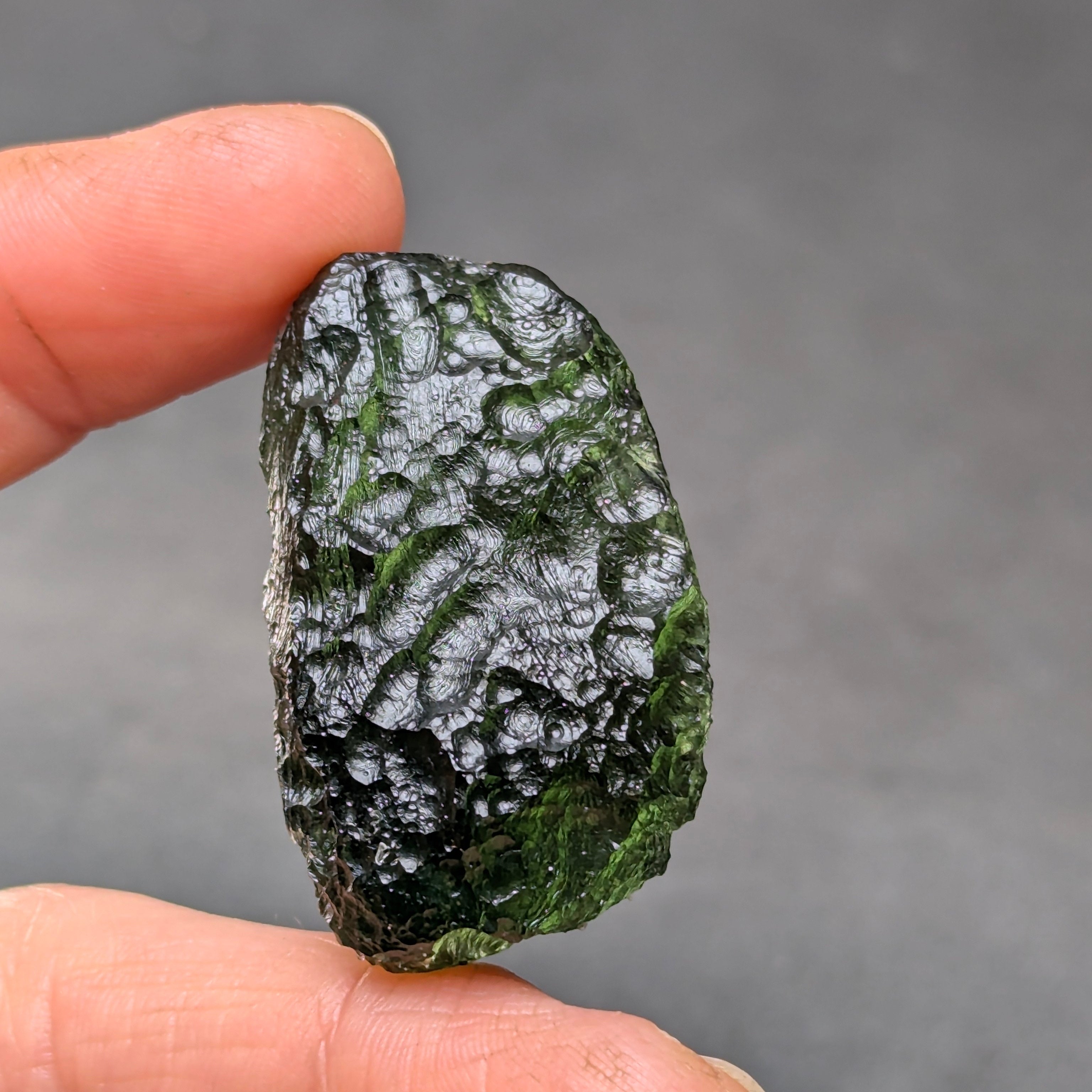 Natural Moldavite from the Krasejovka locality on white background with glossy lacquer-like surface, deep sculpture, pronounced grooves, vivid green translucency and authentic natural relief. Weight 14 g - back side.