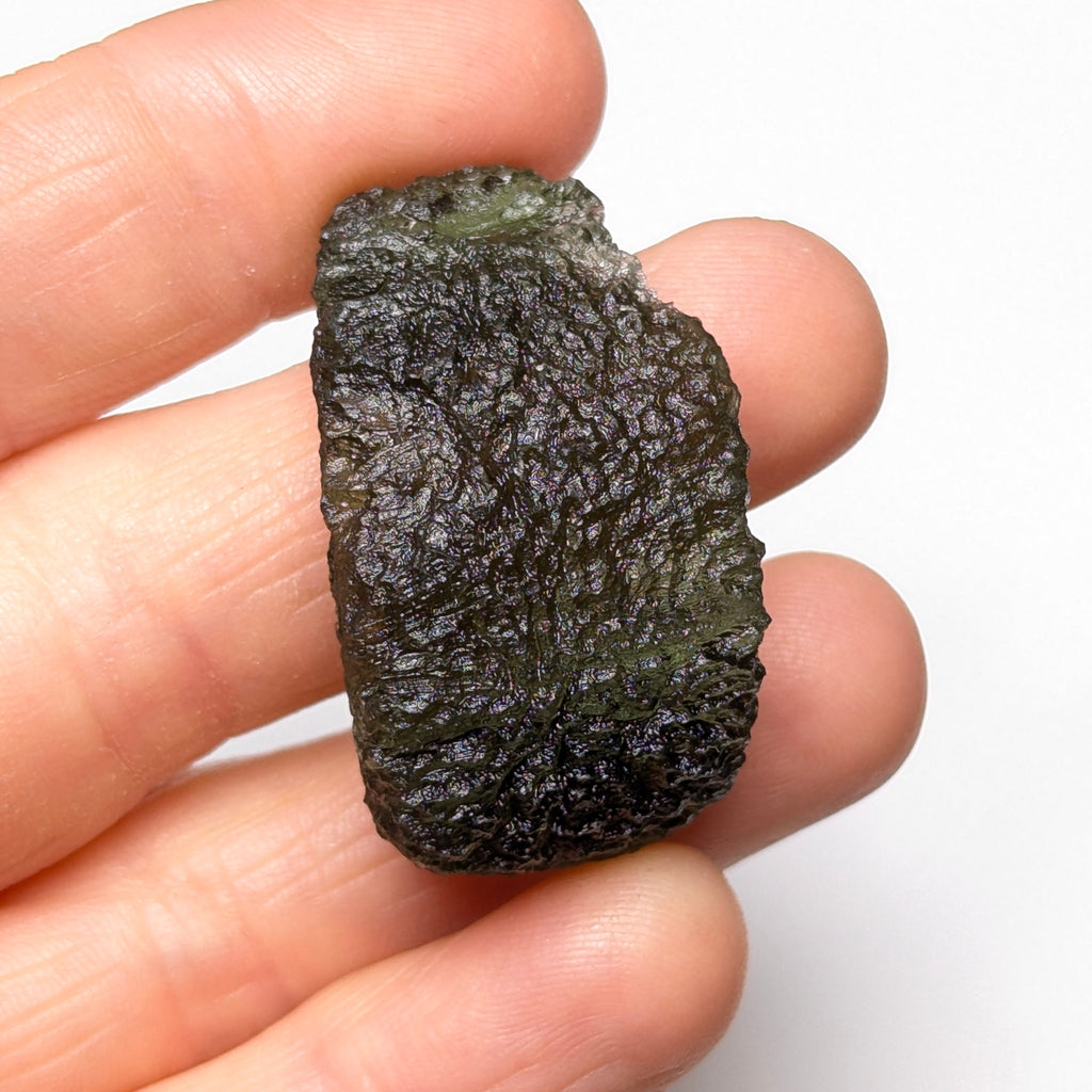 Natural Moldavite from the Olešnice locality weighing 8.86 g with hollow shape, open bubble formation, matte to velvety surface, subtle glossy areas and olive green color in hand - front view.