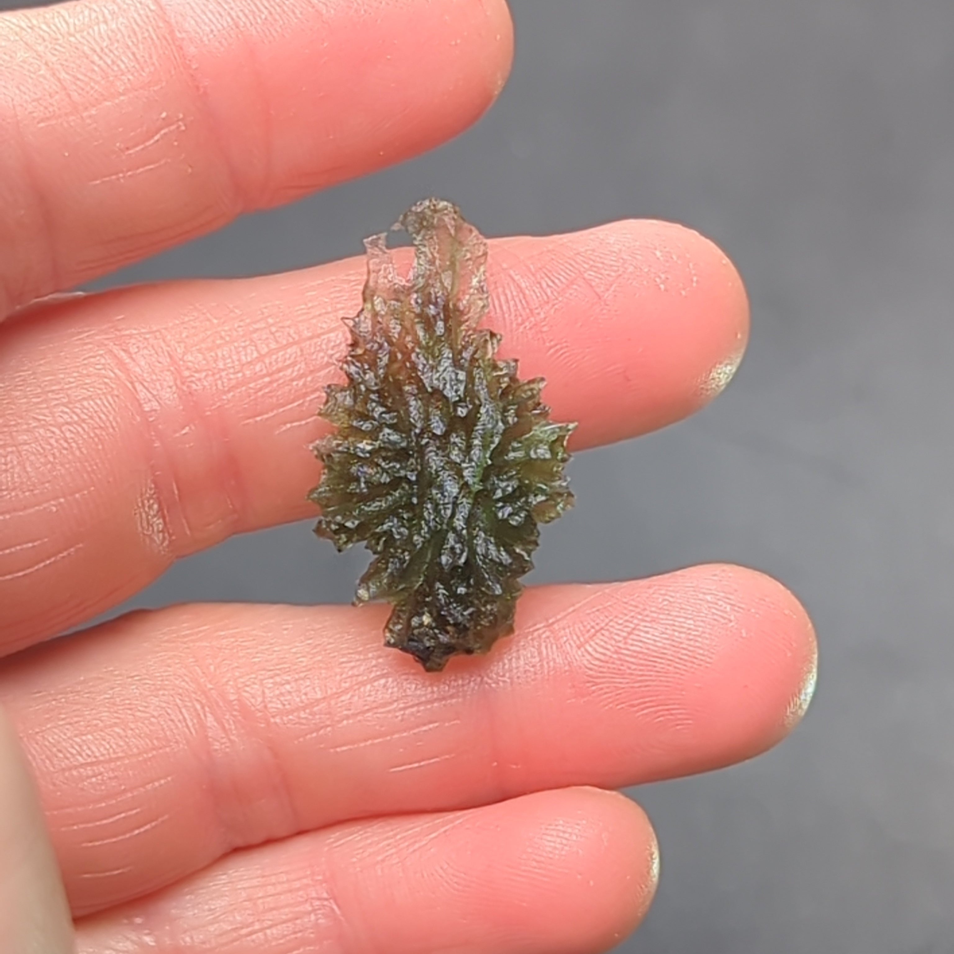 Natural Moldavite from the Besednice Ježkovna locality with sharp hedgehog sculpture, pronounced spikes and authentic natural relief. Weight 2.35 g - front view, in hand.