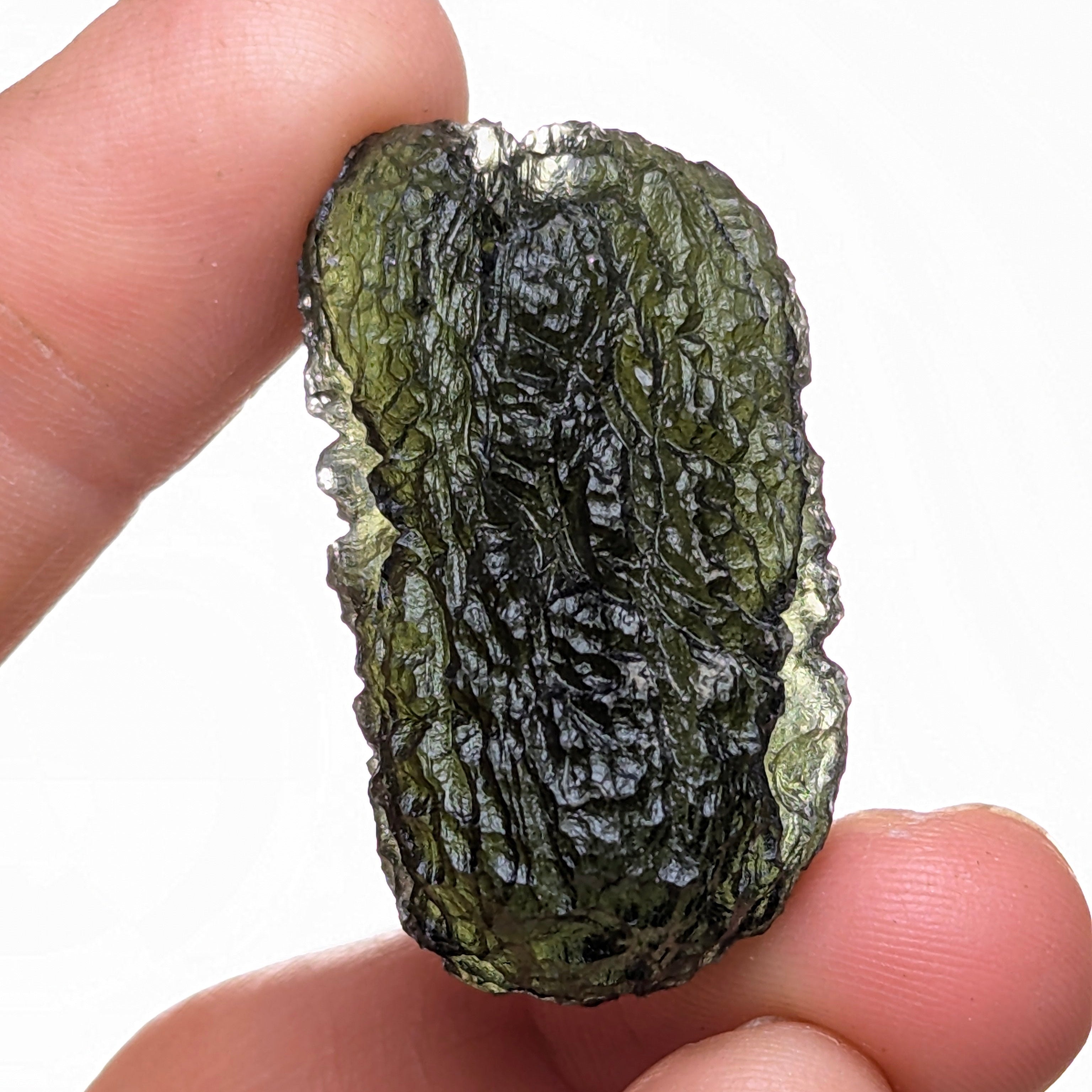 Natural Moldavite from the Olešnice locality with dramatic sculpture, deep central groove, naturally opened bubbles and vivid green translucency under illumination in hand - back side.
