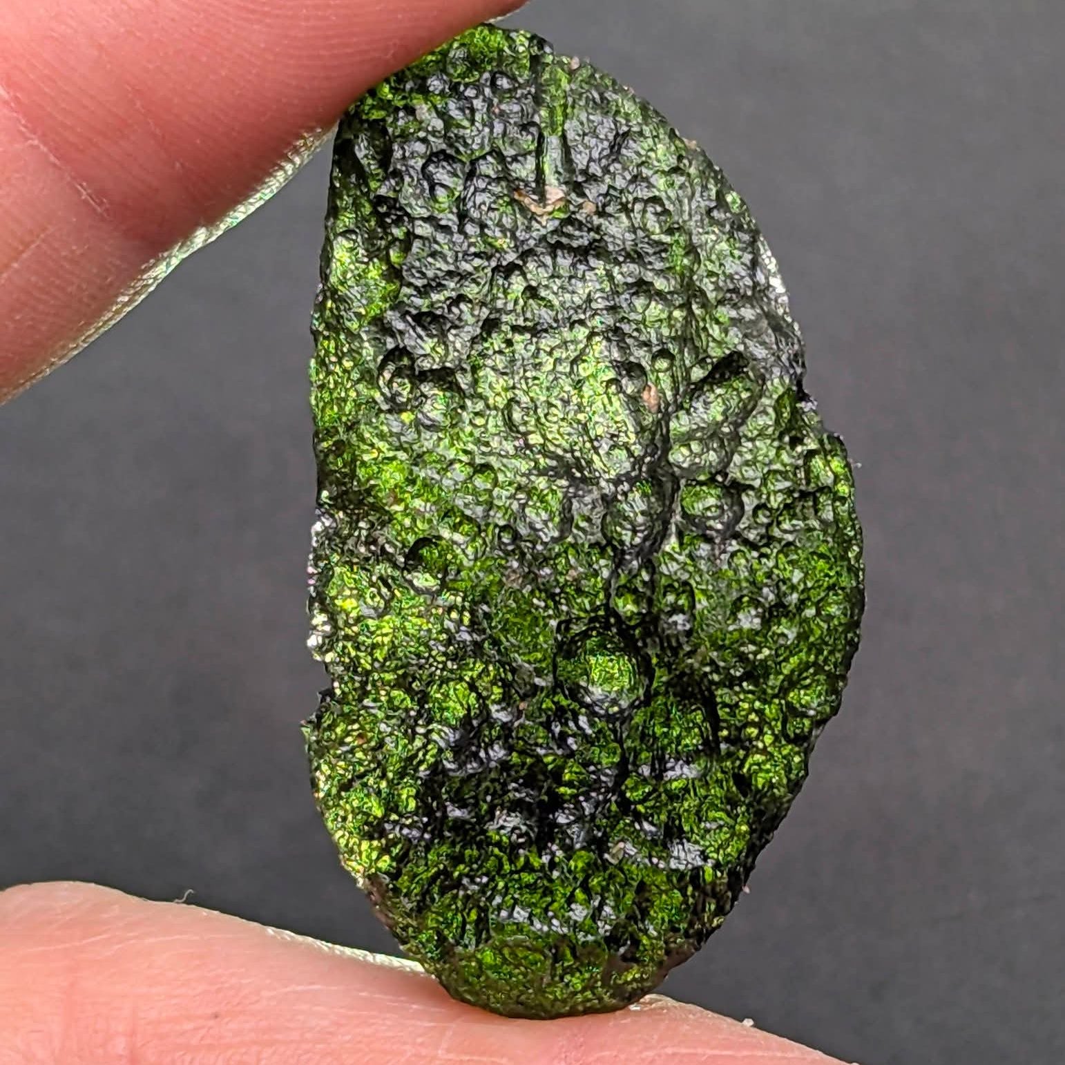 Natural Moldavite from the Něchov locality with deep plastic sculpture, pronounced grooves, dark olive green translucency and authentic natural relief. Weight 8.57 g - front view, backlight.