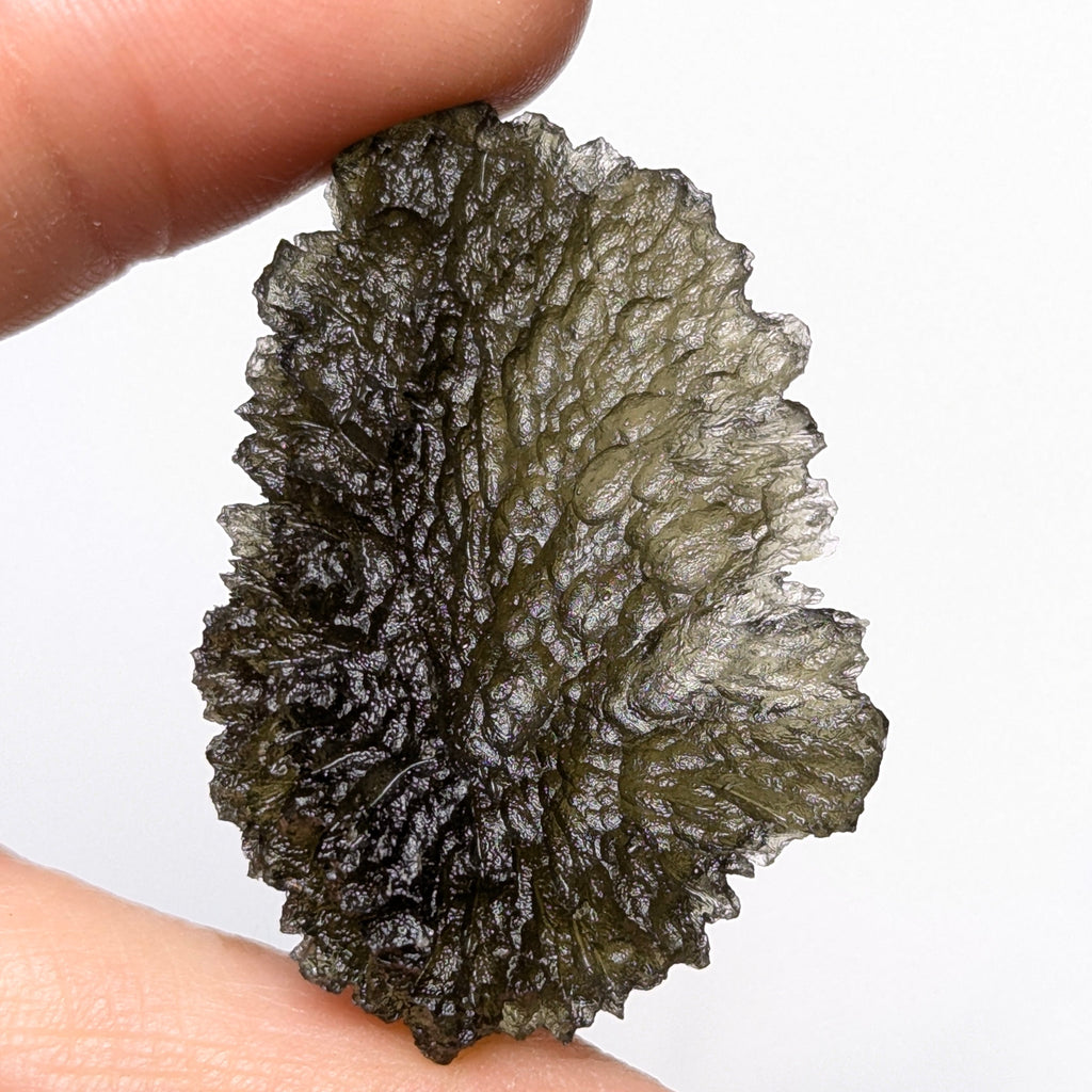 Natural Moldavite from the Olešnice locality with deep sharply sculpted texture, pronounced grooves, complex relief and contrasting green translucency in hand - back side.