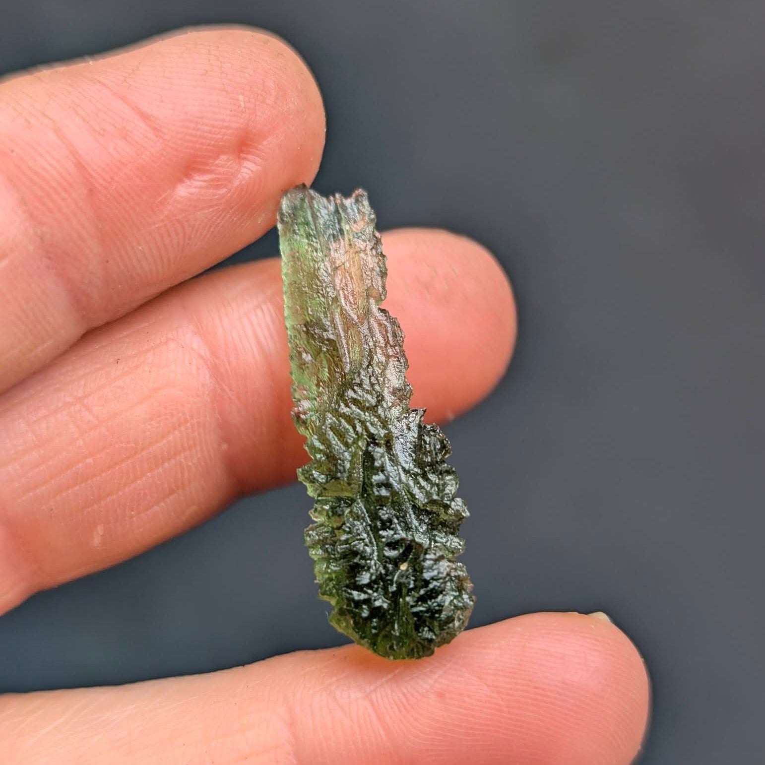 Moldavite Olešnice 1.73g - drop shape, smooth neon green translucent top, dense dark sculpture below - front view.
