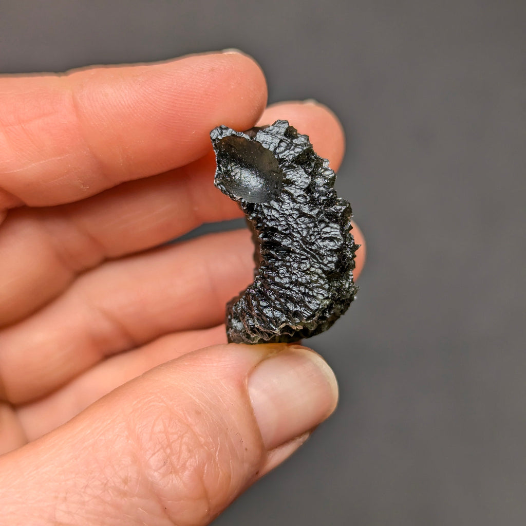 Natural Olešnice 13.87 g moldavite with deep sculpted texture and vivid green translucency under transmitted light - side 2 view.