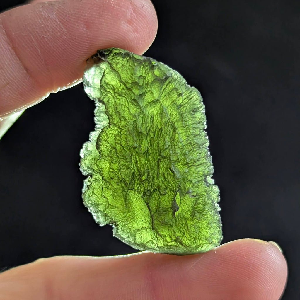 Natural Brusná 10.33 g moldavite with pronounced radial sculpture, deep textured relief and olive-green translucency, backlight. 