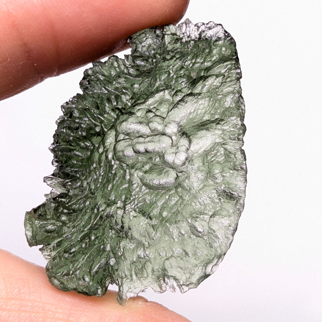 Natural Moldavite from the Olešnice locality with electrifying neon green color, glossy luster, deep grooves and vivid green translucency under illumination in hand - front view.