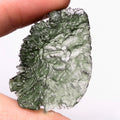 Natural Moldavite from the Olešnice locality with electrifying neon green color, glossy luster, deep grooves and vivid green translucency under illumination in hand - front view.