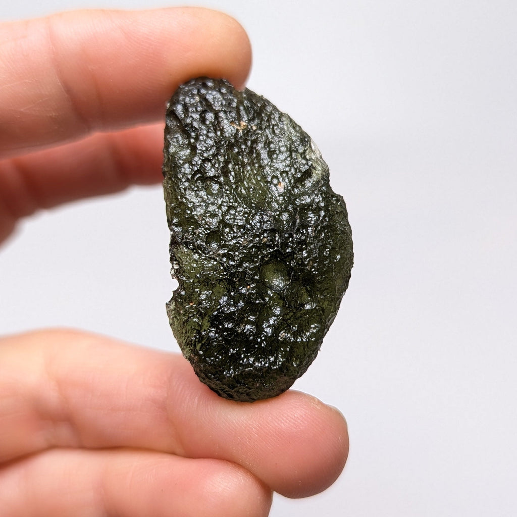 Natural Moldavite from the Něchov locality on white background with deep plastic sculpture, pronounced grooves, dark olive green translucency and authentic natural relief. Weight 8.57 g - front view.