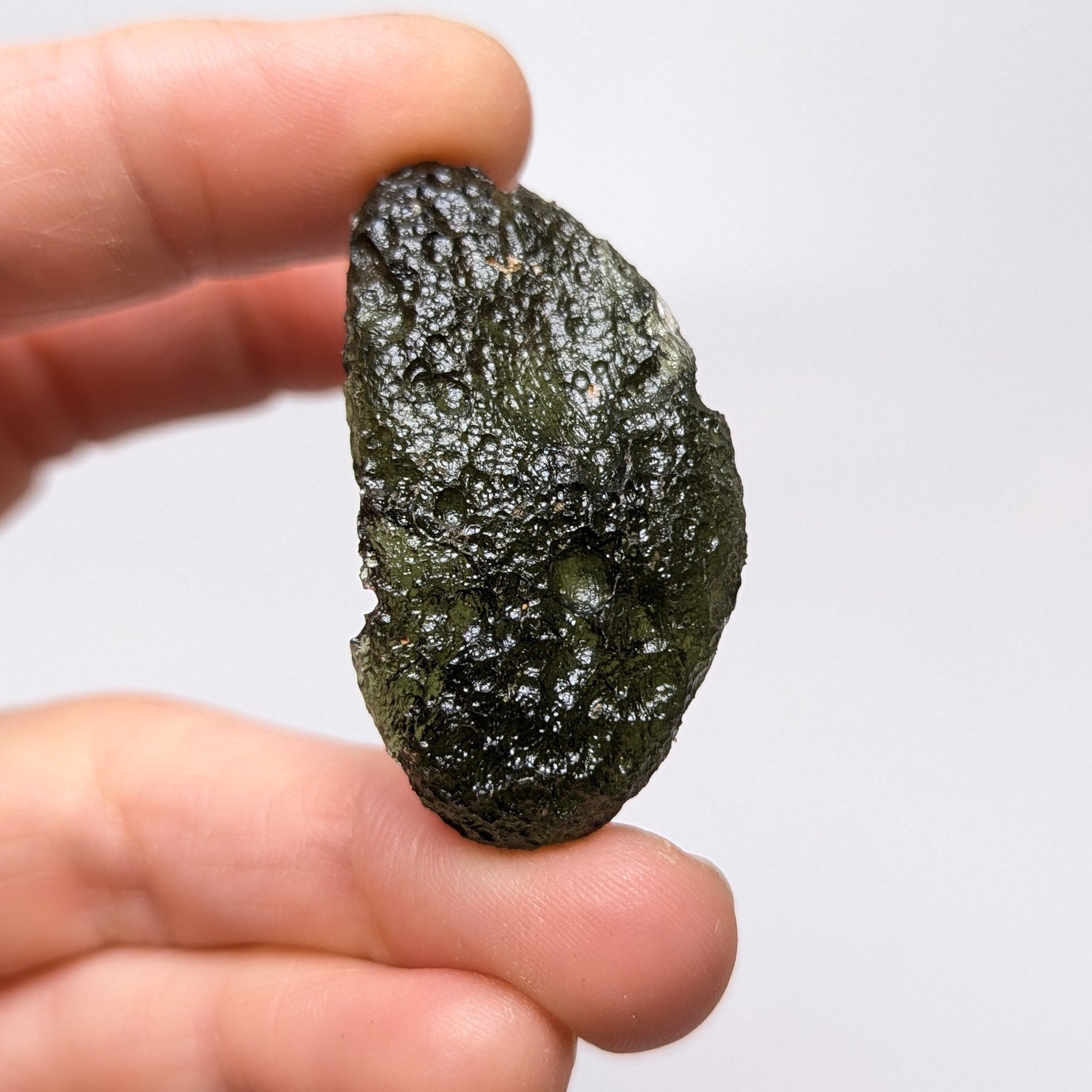 Natural Moldavite from the Něchov locality on white background with deep plastic sculpture, pronounced grooves, dark olive green translucency and authentic natural relief. Weight 8.57 g - front view.
