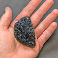Natural moldavite from Krasejovka, 41 g half-disc - front view, in hand.