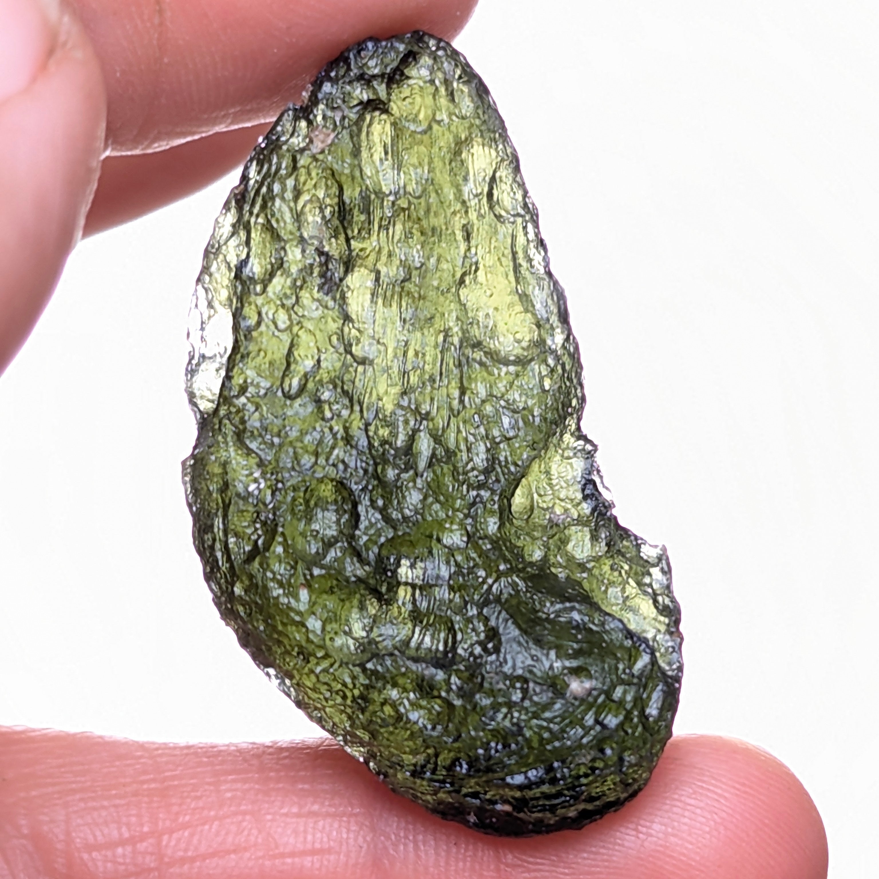 Natural Moldavite from the Něchov locality on white background with deep plastic sculpture, pronounced grooves, dark olive green translucency and authentic natural relief. Weight 8.57 g - back side, backlight.