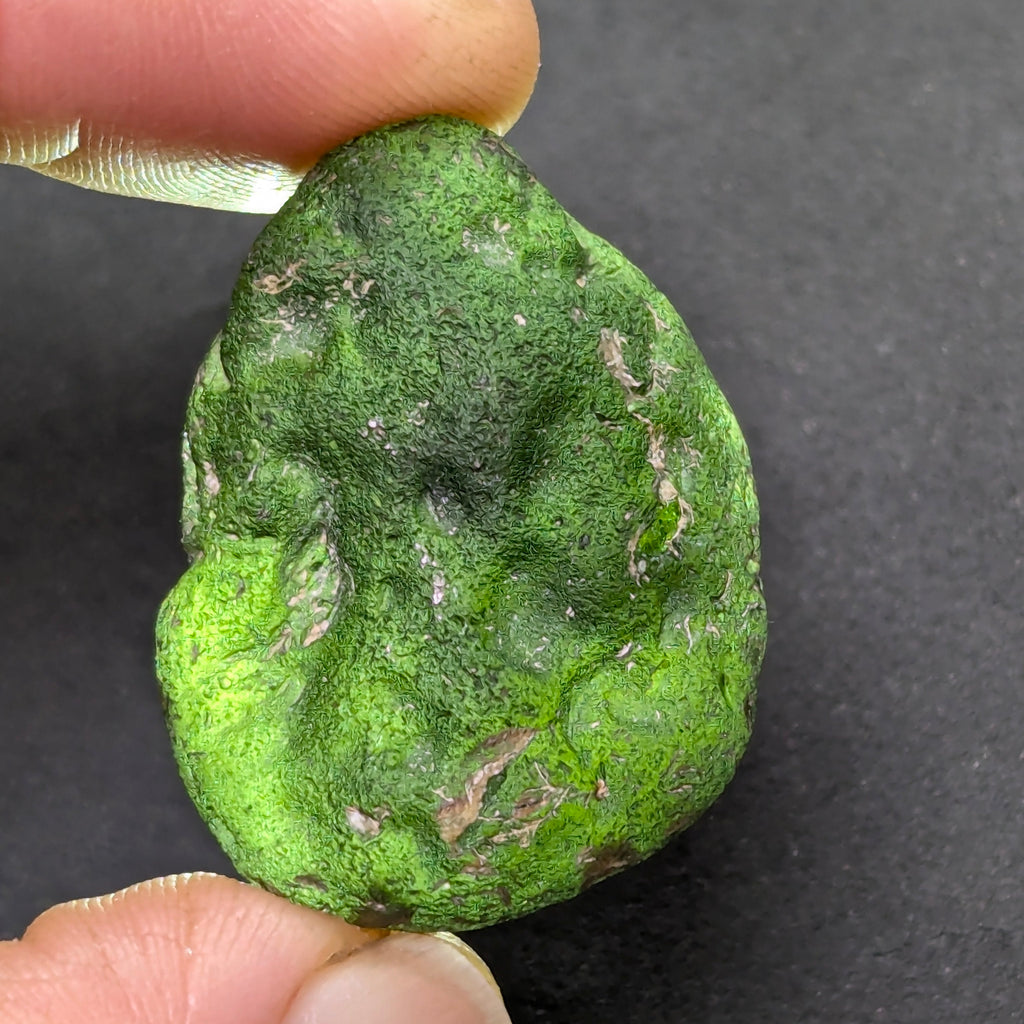 Olive green moldavite 12.5g from Zliv, oval shape with clay residues, backside backlight.