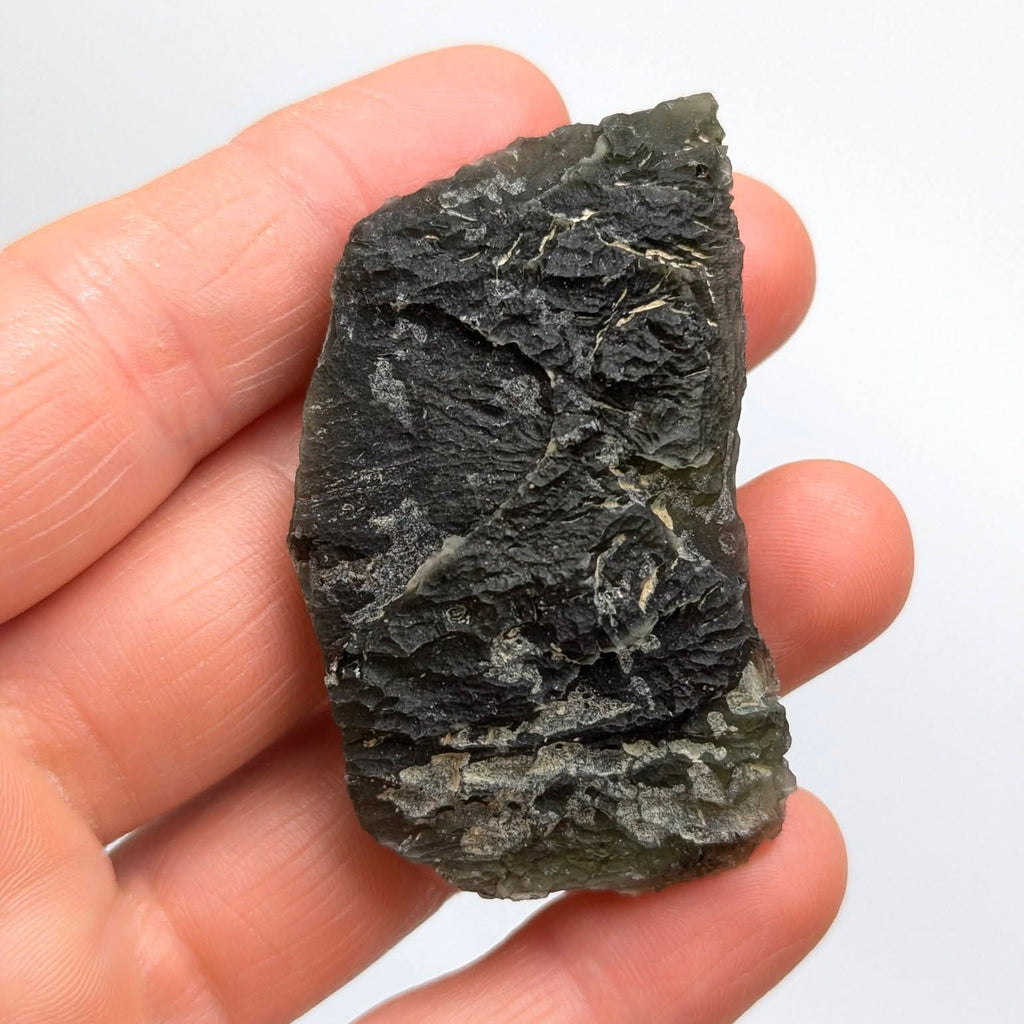 Natural Slavče 25.71 g moldavite with two different sculpting textures and elongated natural shape - white background, front view.
