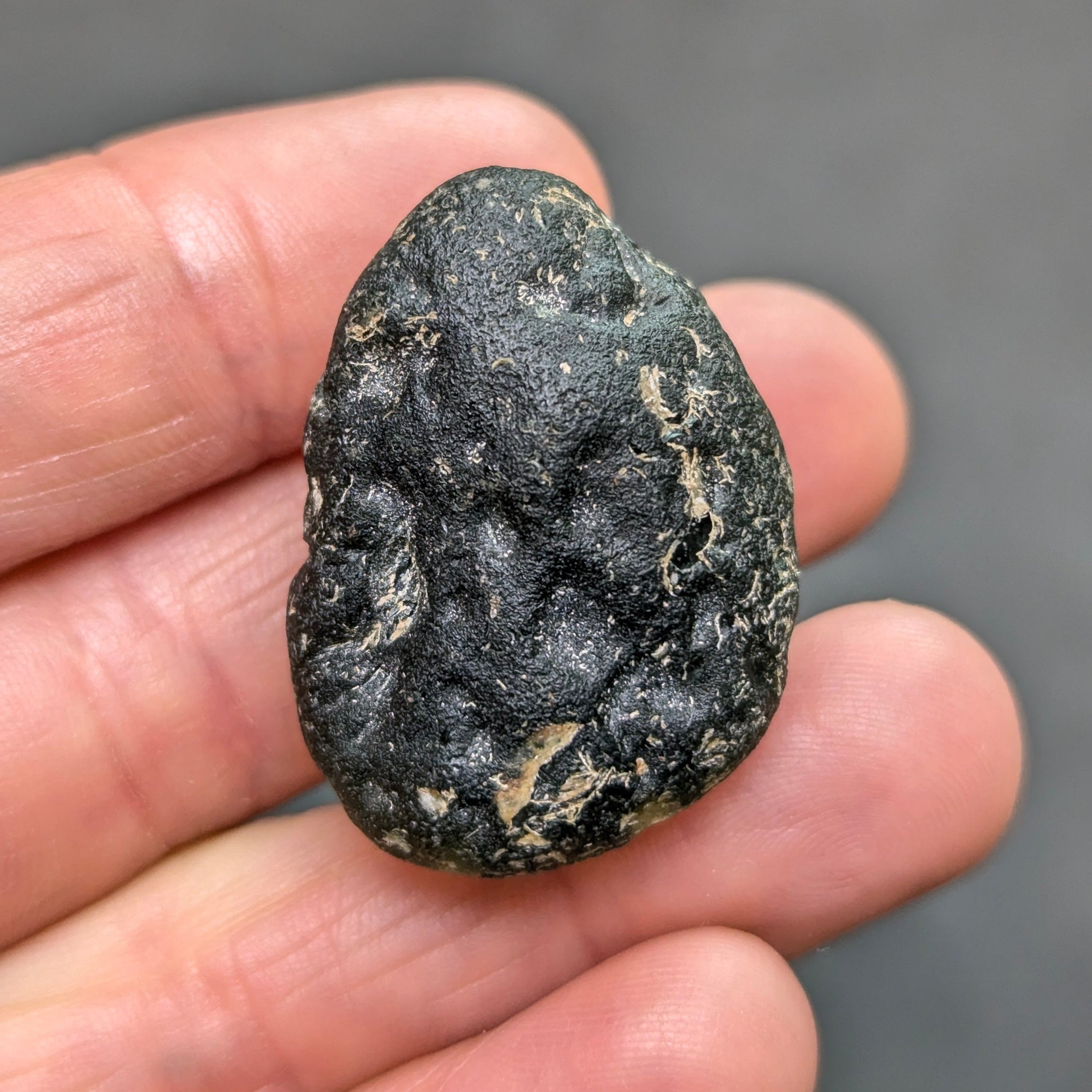 Olive green moldavite 12.5g from Zliv, oval shape with clay residues, back side.