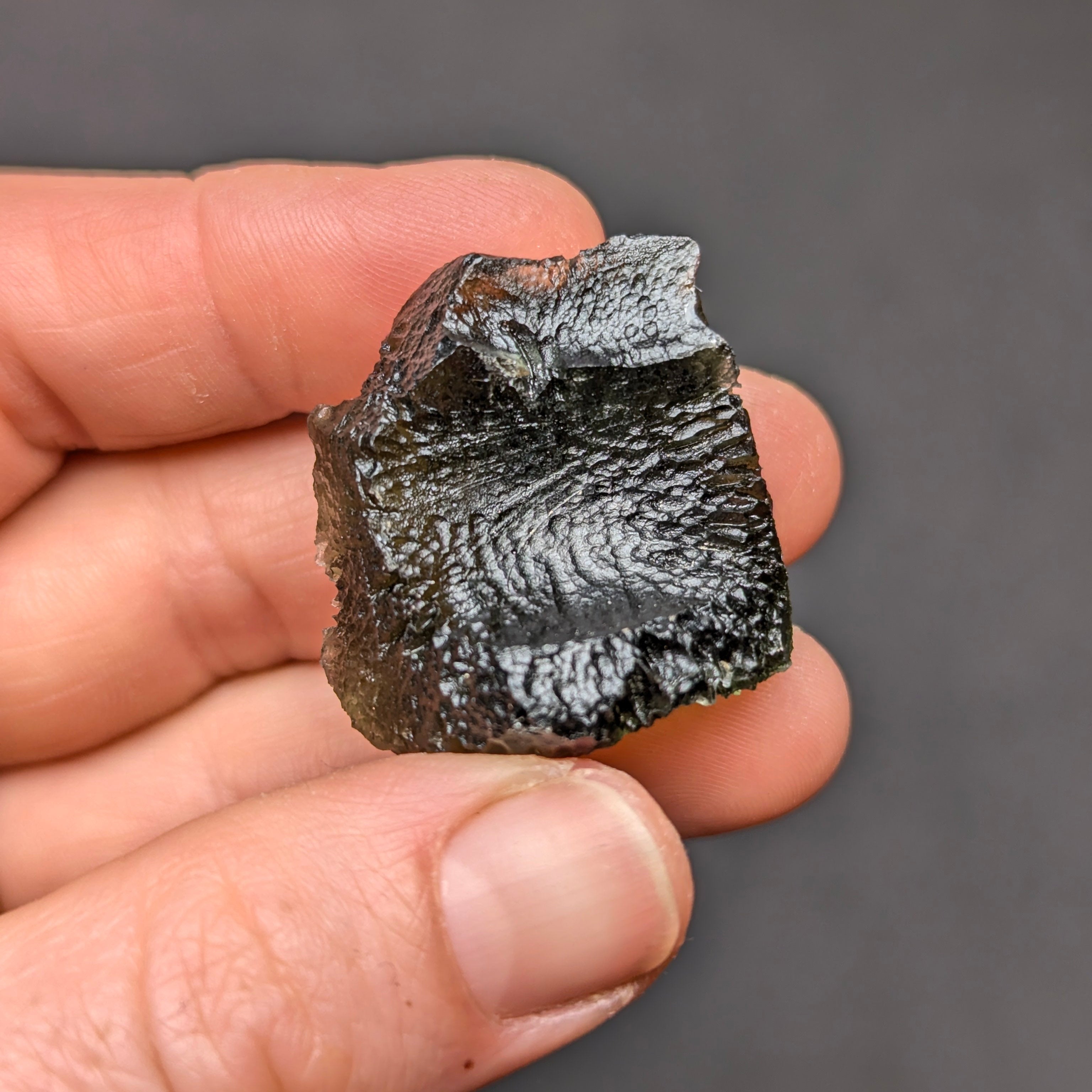Natural Olešnice 13.87 g moldavite with deep sculpted texture and vivid green translucency under transmitted light - back side.