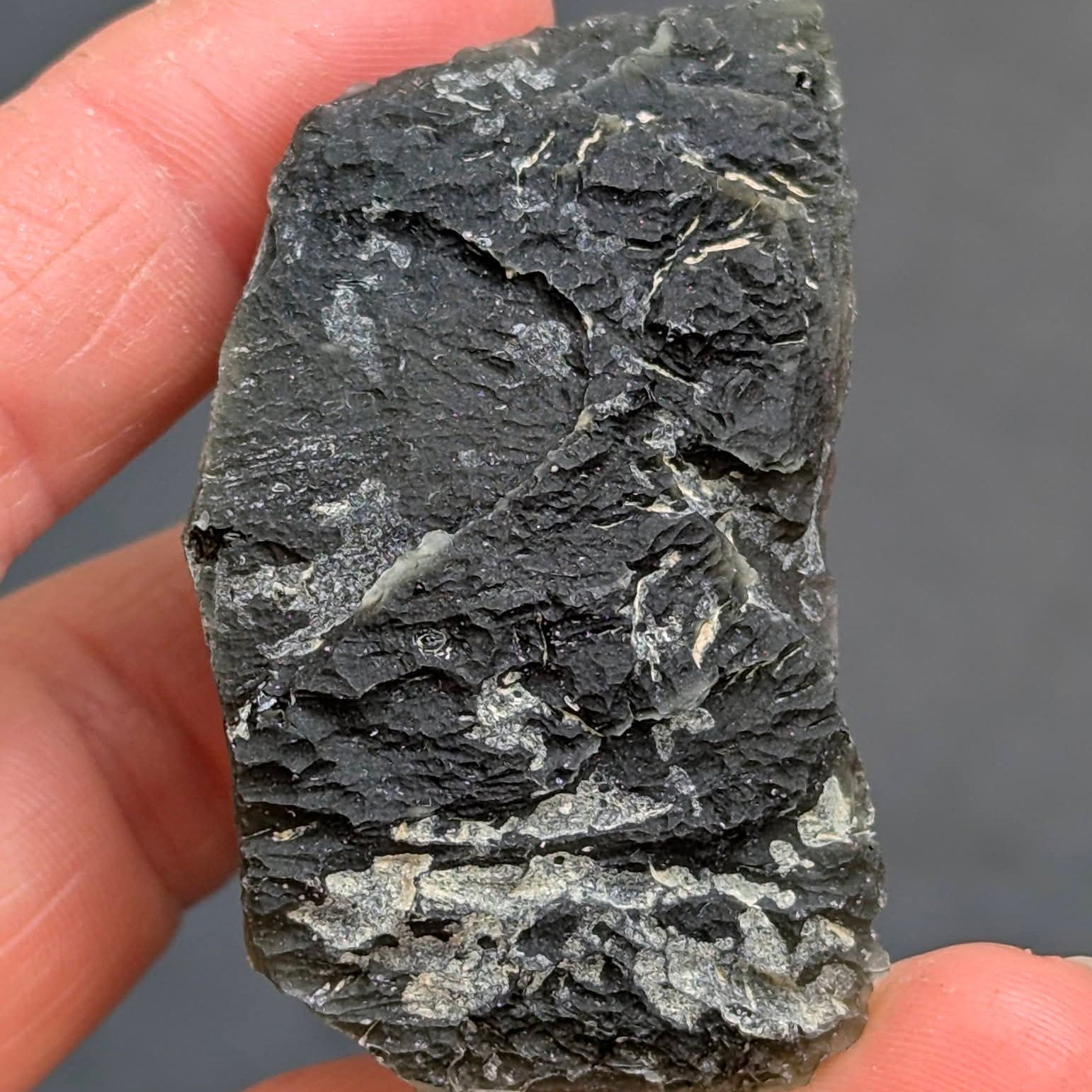 Natural Slavče 25.71 g moldavite with two different sculpting textures and elongated natural shape - front view.