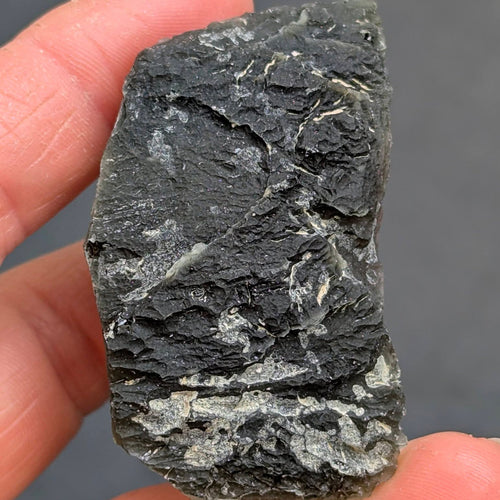 Natural Slavče 25.71 g moldavite with two different sculpting textures and elongated natural shape - front view.