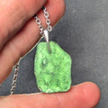 Natural Radomilice 4 g moldavite pendant with Ag 925 silver bail, light yellow-green color and naturally rounded sculpted surface - front side, backlight.