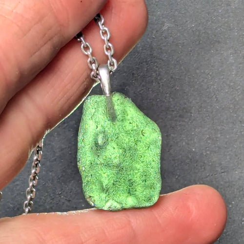 Natural Radomilice 4 g moldavite pendant with Ag 925 silver bail, light yellow-green color and naturally rounded sculpted surface - front side, backlight.