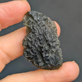 Natural Brusná 10.33 g - moldavite with pronounced radial sculpture, deep textured relief and olive-green translucency, front view.